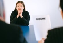 A woman in a job interview facing two employers with a focus on her resume.