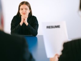 A woman in a job interview facing two employers with a focus on her resume.