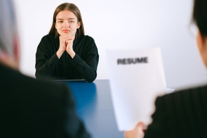 A woman in a job interview facing two employers with a focus on her resume. A woman in a job interview facing two employers with a focus on her resume.