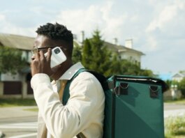 A young delivery man talks on his smartphone while carrying a thermal delivery bag outdoors.