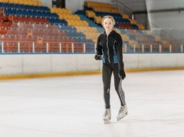 A young woman glides gracefully on an indoor ice rink, showcasing her skating skills.