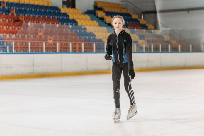 A young woman glides gracefully on an indoor ice rink, showcasing her skating skills.