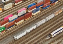 Правительство Канады отметило торжественное открытие объекта CANXPORT Aerial shot showcasing colorful freight containers on train tracks in a busy transportation yard.