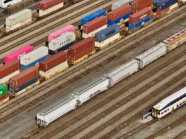 Aerial shot showcasing colorful freight containers on train tracks in a busy transportation yard.