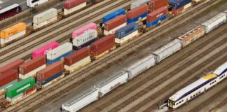 Aerial shot showcasing colorful freight containers on train tracks in a busy transportation yard.