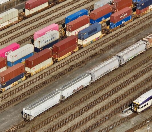Aerial shot showcasing colorful freight containers on train tracks in a busy transportation yard.