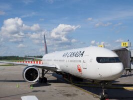 Air Canada Boeing 777 airplane parked at an airport gate under a clear blue sky.