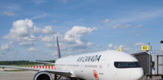 Air Canada Boeing 777 airplane parked at an airport gate under a clear blue sky.