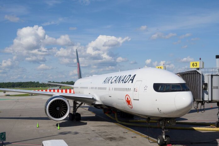 Air Canada Boeing 777 airplane parked at an airport gate under a clear blue sky. Air Canada Boeing 777 airplane parked at an airport gate under a clear blue sky.