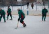 Amateur ice hockey match in snow-filled setting with players in green uniforms.