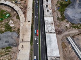An aerial shot of a busy highway flanked by construction sites, showcasing urban development.