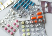 Assorted colorful blister packs of pills and capsules on a white surface.