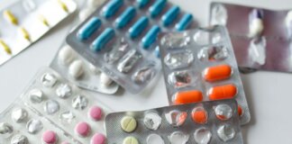 Assorted colorful blister packs of pills and capsules on a white surface.