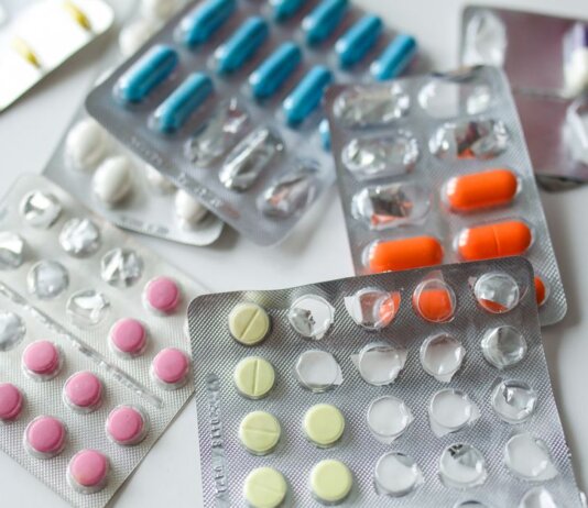 Assorted colorful blister packs of pills and capsules on a white surface.