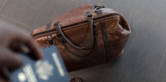 Brown leather bag with passport in an airport setting, ideal for travel and fashion themes.