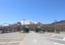 Canadian border crossing amidst stunning snow-capped mountains and clear blue sky.