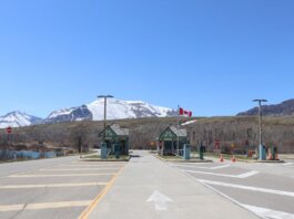 Canadian border crossing amidst stunning snow-capped mountains and clear blue sky.