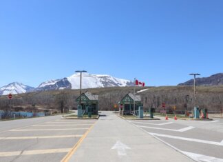 Canadian border crossing amidst stunning snow-capped mountains and clear blue sky.