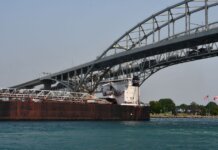 Cargo ship passing under the Blue Water Bridge connecting USA and Canada on a clear day.