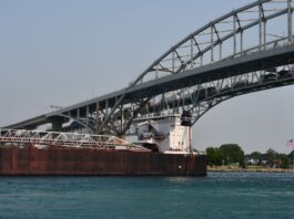 Cargo ship passing under the Blue Water Bridge connecting USA and Canada on a clear day.