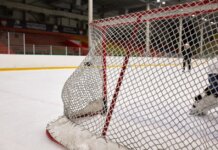 «Виннипег Джетс» уступили «Монреалю» 1:2 в Heritage Classic и проиграли пятый матч подряд Close-up of a hockey goal on an indoor rink with players practicing in the background.