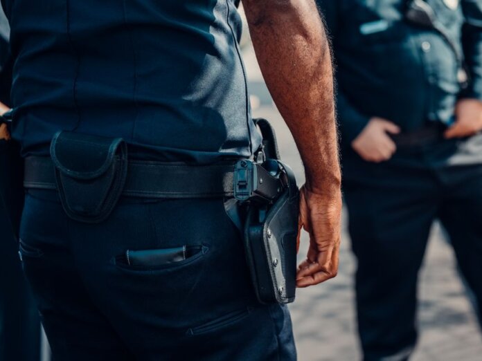 Close-up of a police officer's firearm securely holstered at the waist, conveying professionalism and readiness. Close-up of a police officer's firearm securely holstered at the waist, conveying professionalism and readiness.