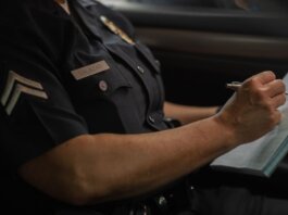 Close-up of a police officer writing in a notebook while sitting in a car, focused detail.