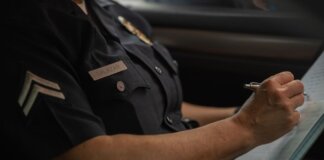 Close-up of a police officer writing in a notebook while sitting in a car, focused detail.