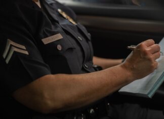 Close-up of a police officer writing in a notebook while sitting in a car, focused detail.