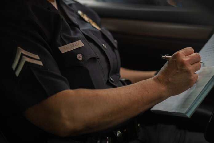 Close-up of a police officer writing in a notebook while sitting in a car, focused detail. Close-up of a police officer writing in a notebook while sitting in a car, focused detail.