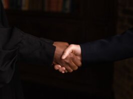 Close-up of diverse individuals shaking hands, symbolizing business agreement.