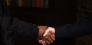 Close-up of diverse individuals shaking hands, symbolizing business agreement.