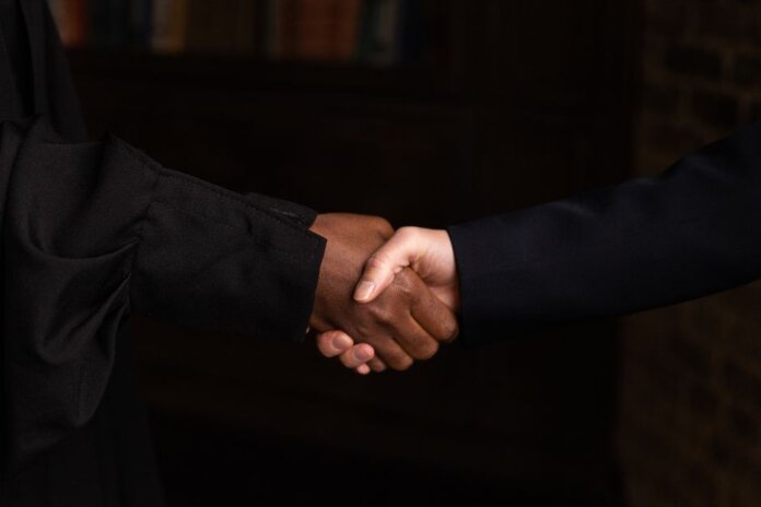 Close-up of diverse individuals shaking hands, symbolizing business agreement. Close-up of diverse individuals shaking hands, symbolizing business agreement.