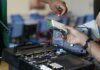 Стартап UBC Dream Photonics меняет производство передовых технологий в Британской Колумбии Close-up of hands working with electronics equipment and circuit board in a lab setting.