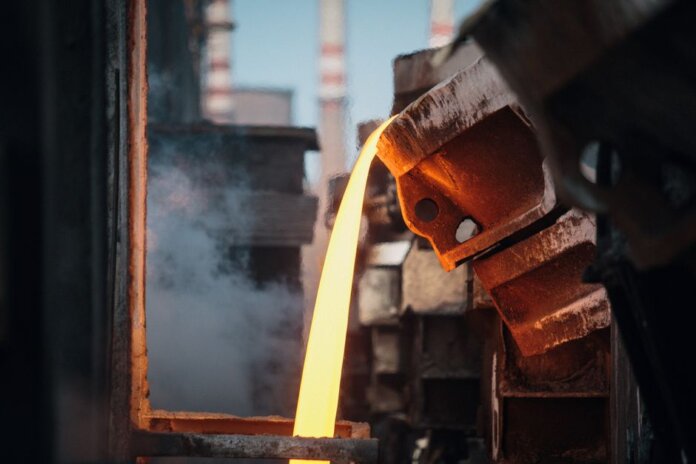 Close-up of molten metal pouring in a foundry, showcasing industrial processes. Close-up of molten metal pouring in a foundry, showcasing industrial processes.