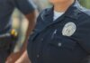 Close-up of police officers in uniform, displaying badge and radio outdoors.