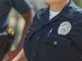 Close-up of police officers in uniform, displaying badge and radio outdoors.