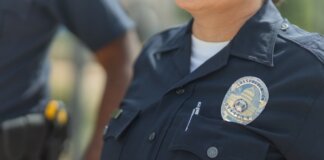 Close-up of police officers in uniform, displaying badge and radio outdoors.