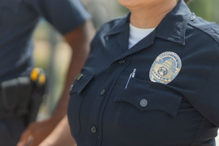 Close-up of police officers in uniform, displaying badge and radio outdoors. Close-up of police officers in uniform, displaying badge and radio outdoors.