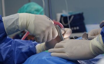 14-летняя Клоэ стала первой пациенткой в Манитобе, перенёсшей операцию sEEG на мозге Close-up of surgeons operating in a hospital theater setting with precision.