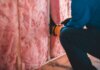 Оттава проведёт технический брифинг о новых мерах по энергоэффективности жилья Crop unrecognizable worker in gloves sitting on haunches and insulating with pink stone wool