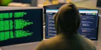 Хакер в капюшоне за несколькими мониторами