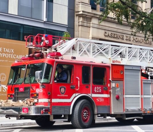 Detailed view of a red fire truck in Montreal with building background.