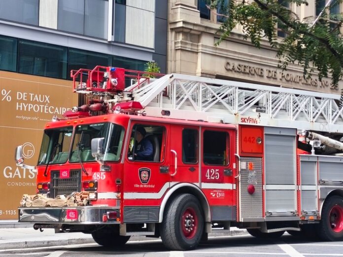 Detailed view of a red fire truck in Montreal with building background.