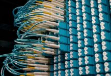 Detailed view of fiber optic patch cables connecting to a blue patch panel in a data center.