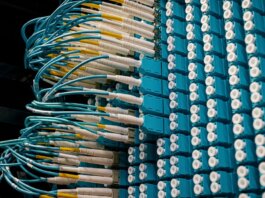 Detailed view of fiber optic patch cables connecting to a blue patch panel in a data center.