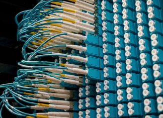 Канада и Альберта расширят доступ к высокоскоростному интернету в общинах провинции Detailed view of fiber optic patch cables connecting to a blue patch panel in a data center.