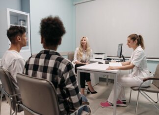 Doctors talking with patients during a medical appointment in a clinic office setting.