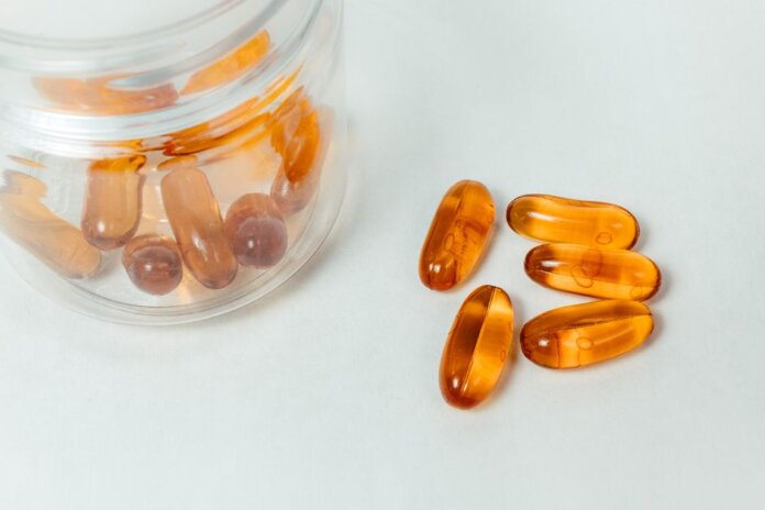 Glass container with amber capsules spilling out on a white background. Glass container with amber capsules spilling out on a white background.