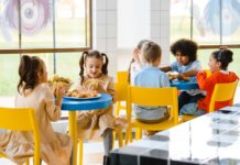 Group of children eating together at a school cafeteria, sharing joy and food.